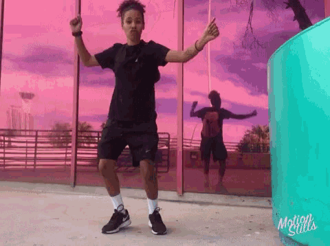 a woman is dancing in front of a pink building that says motion stills on the bottom