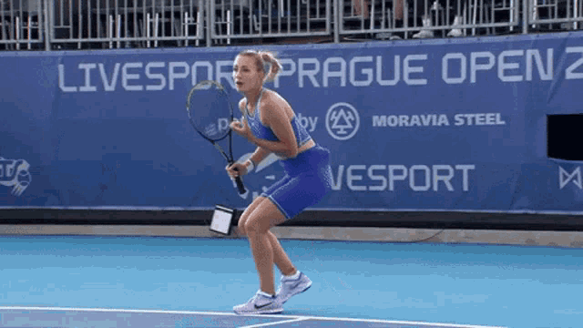 a woman is holding a tennis racquet in front of a banner that says livesport prague open 2
