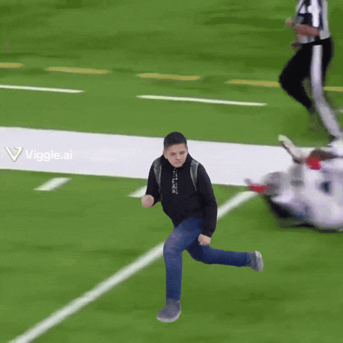 a young man in a black sweatshirt and jeans is jumping in the air on a purple field