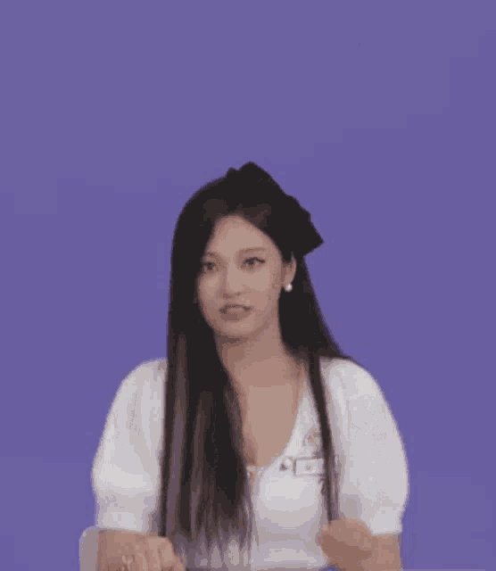 a woman with long black hair is wearing a white shirt and a black bow on her head .