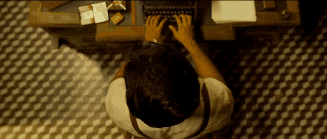 a man sits at a desk typing on a keyboard