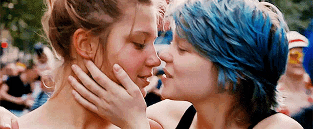 two women with blue hair are kissing each other on the forehead .