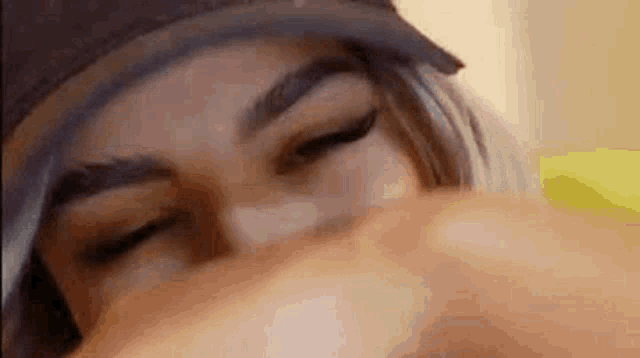 a close up of a woman 's face with her eyes closed and her hand on her face .