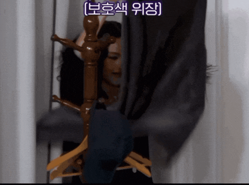a woman is standing in a closet behind a clothes rack with chinese writing on the bottom right