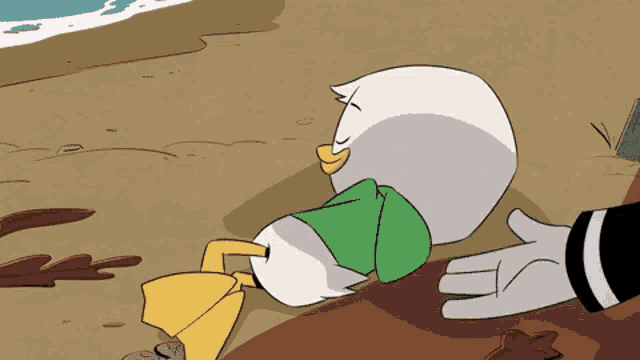 a cartoon duck is laying on the ground next to a hand