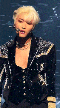 a man with blonde hair is wearing a sequined jacket and a necklace