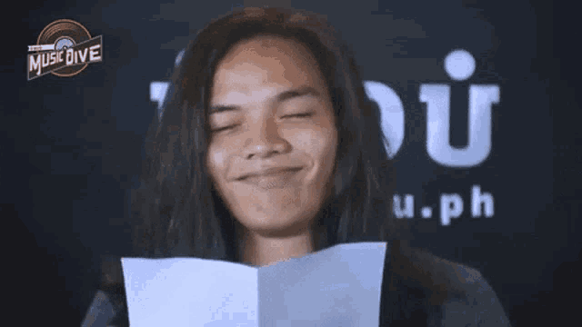 a man with long hair is holding a piece of paper in front of a music dive logo