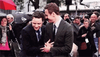 two men in suits and ties are hugging in front of a crowd .