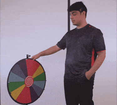 a man stands in front of a colorful spinning wheel