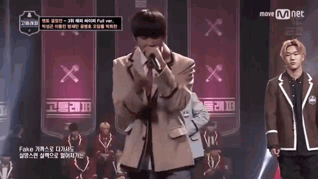 a man is singing into a microphone on a stage in front of a sign that says move mnet on it