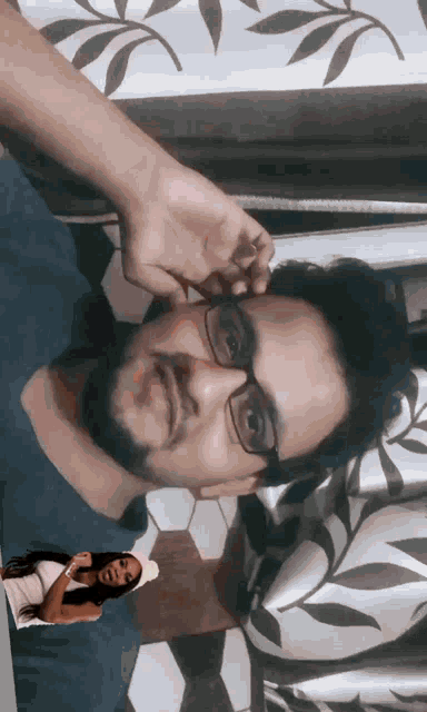 a man with glasses and a beard has a picture of a woman behind him