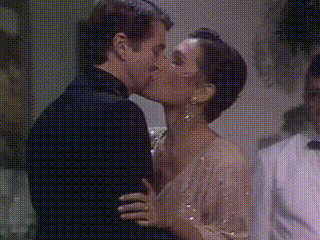 a man and a woman are kissing in a room .