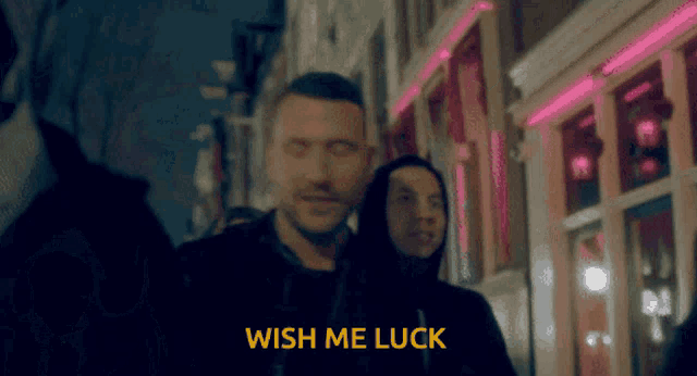 a man walking down a street with the words wish me luck in yellow