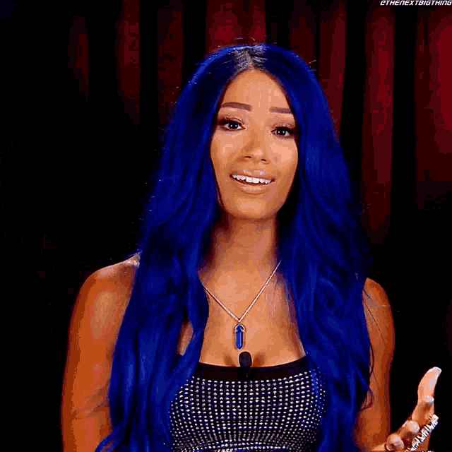 a woman with blue hair is standing in front of a banner that says raw sasha banks
