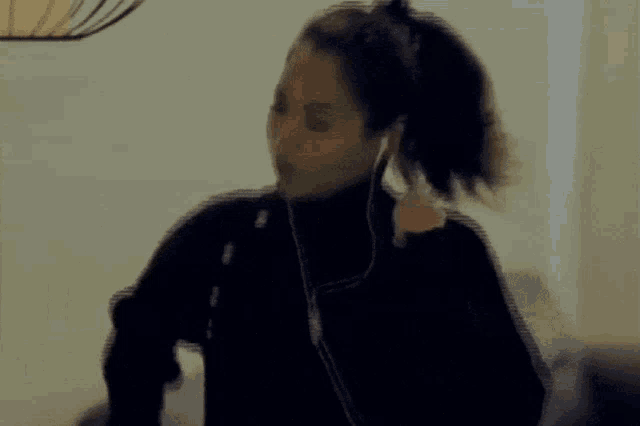 a woman wearing headphones and a ponytail is dancing in a living room
