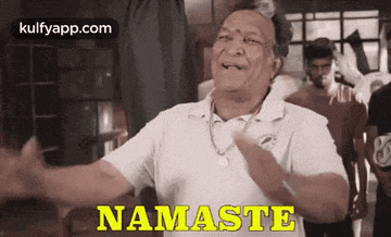 a man in a white shirt is standing in a room with his arms outstretched and saying namaste .