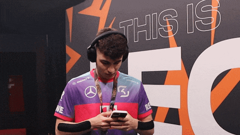 a man wearing headphones is looking at his phone in front of a wall that says this is