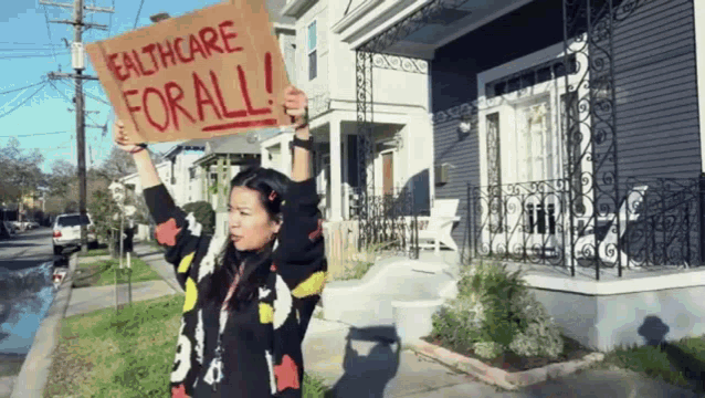 a woman holds a sign that says healthcare for all