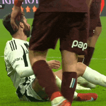 a soccer player wearing a pap shorts is laying on the ground