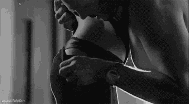 a man is taking off a woman 's bra in a black and white image .