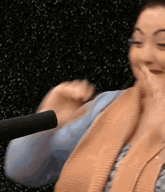 a woman in a sweater is sitting in front of a microphone .