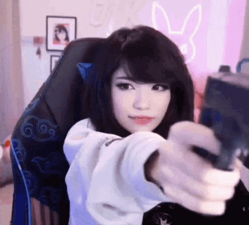 a girl is sitting in a chair holding a gun and taking a picture of herself .