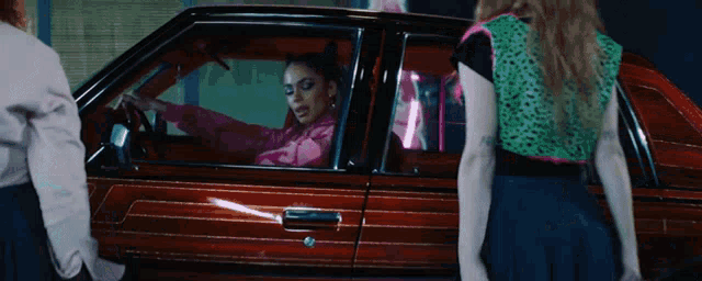 a woman in a pink jacket sits in a red car