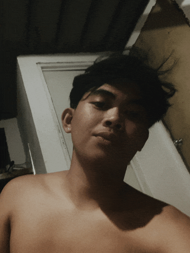 a shirtless man is taking a selfie in front of a white door
