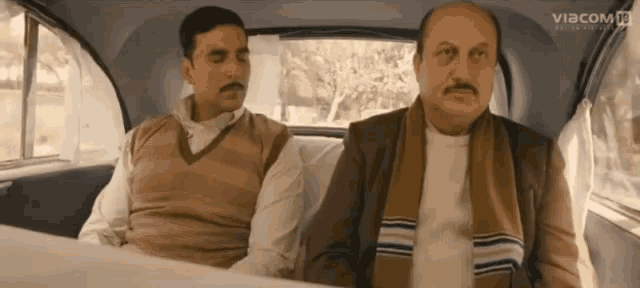 two men are sitting in the back seat of a car with the word viacom on the bottom right