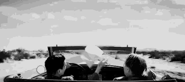 a man and a woman are sitting in a convertible car .