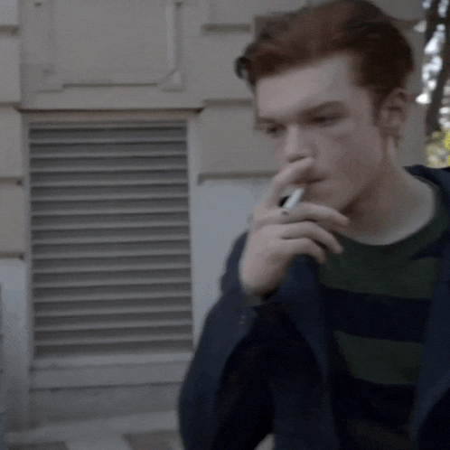 a man with red hair is smoking a cigarette