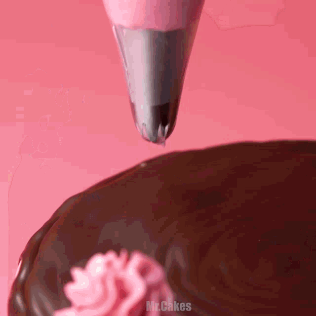 a close up of a cake being decorated with pink frosting