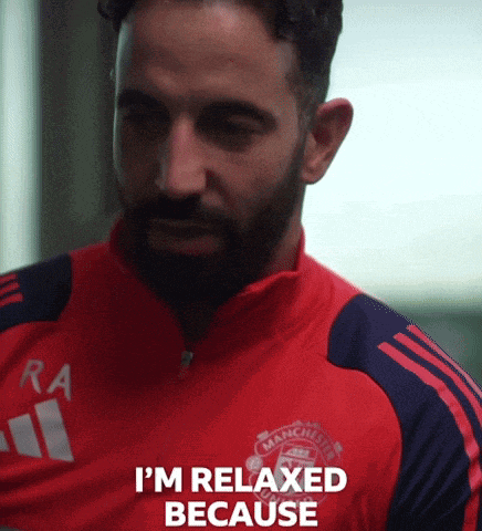 a man with a beard wearing a red manchester united shirt