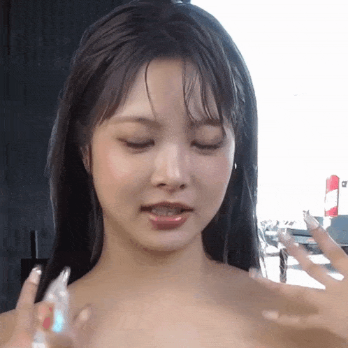 a close up of a woman 's face while holding a bottle