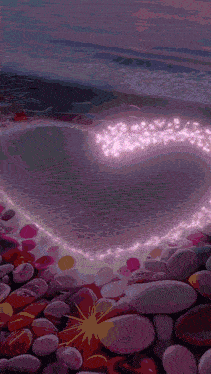 a heart made of lights is surrounded by rocks on the beach