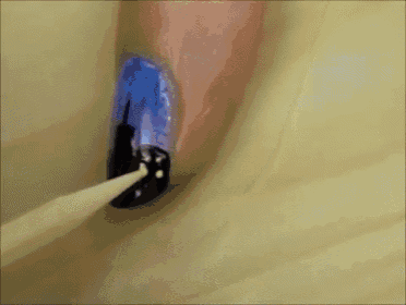 a close up of a nail being painted with blue and black