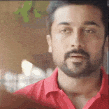 a man with a beard is wearing a red shirt and making a funny face .
