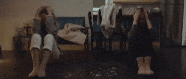 a woman is sitting on the floor with her head in her hands .