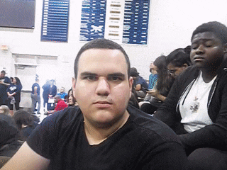 a man in a black shirt is sitting in front of a crowd of people