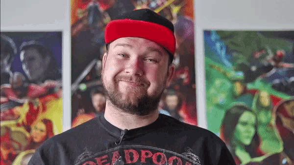a man wearing a red hat and a black deadpool shirt