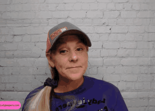 a woman wearing a hat and a purple shirt with the word volleyball on it