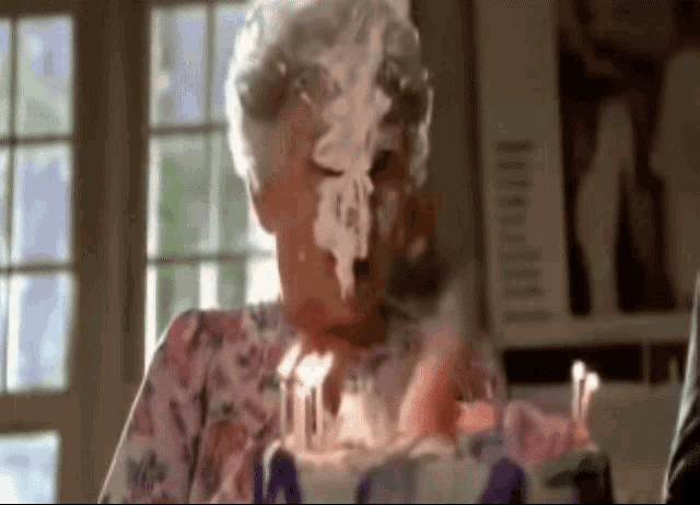 a woman is blowing out candles on a birthday cake