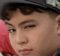 a close up of a person 's face wearing a hat and looking at the camera .