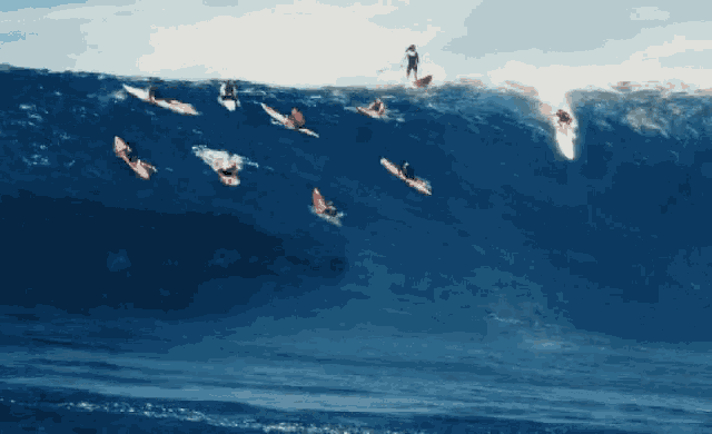 a group of surfers riding a large wave