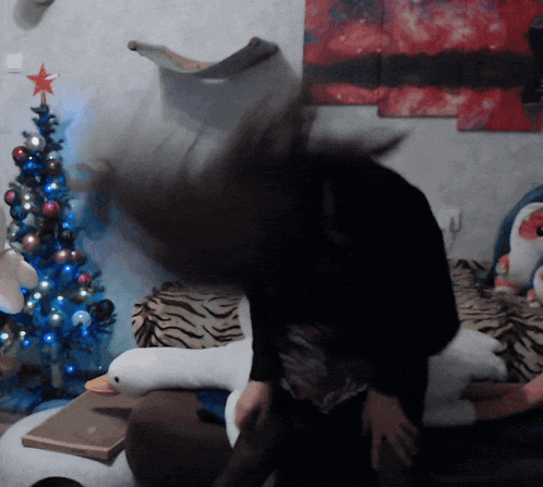 a woman throws her hair in the air in front of a christmas tree and stuffed animals