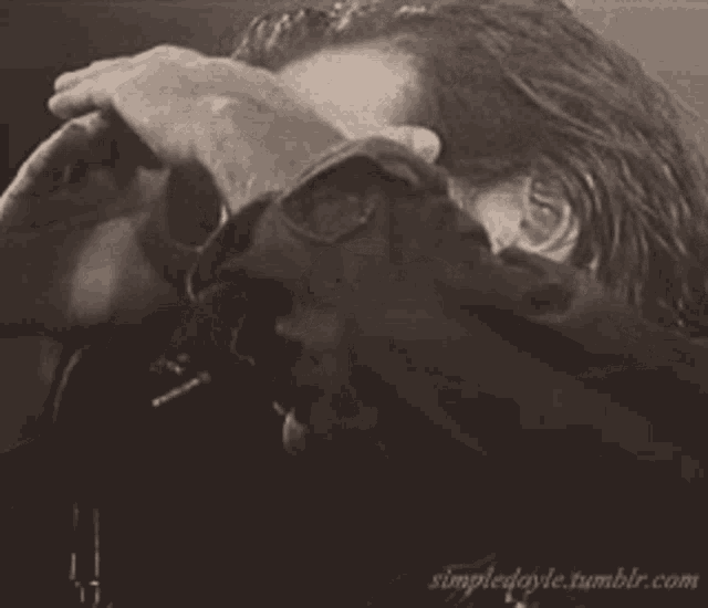 a black and white photo of a man with his hands on his face