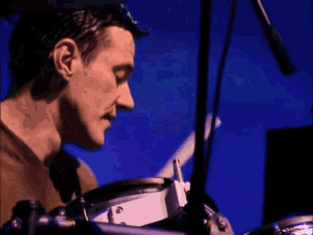 a man is playing a drum set in front of a blue background