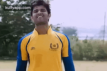 a young man in a yellow and blue soccer jersey is smiling .