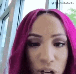 a woman with pink hair is looking at the camera and making a funny face .