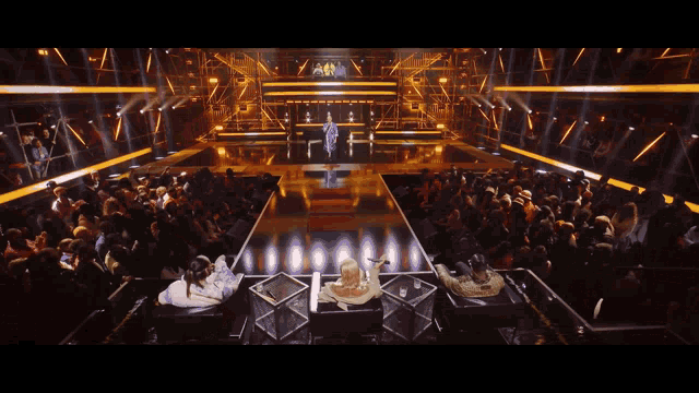a group of people are sitting in front of a stage with a sign that says ama